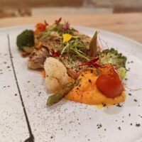 Plato gourmet con vegetales y puré de calabaza.