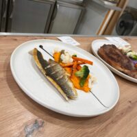 Plato de pescado con verduras en restaurante.