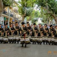 Desfile tradicional en Dénia con mujeres vestidas de negro.