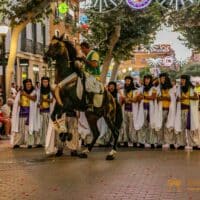 Desfile de moros y cristianos en una calle concurrida.
