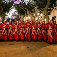 Desfile de personas vestidas con trajes medievales rojos.