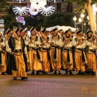 Desfile festivo en la calle con trajes tradicionales.