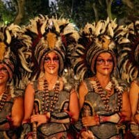 Personas en disfraces tribales con plumas y calaveras