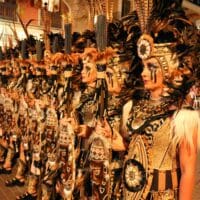 Desfile de personas con trajes indígenas festivos.