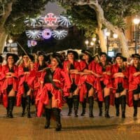 Grupo de personas desfilando con trajes rojos y negros