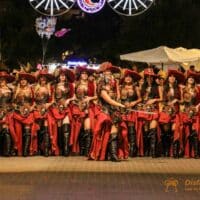 Desfile de mujeres disfrazadas en fiesta nocturna.