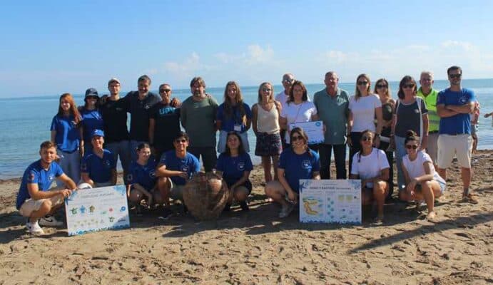 Voluntarios en la playa con carteles informativos.