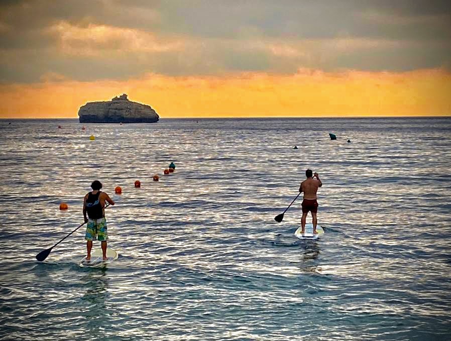 Dos personas practicando paddle surf al atardecer