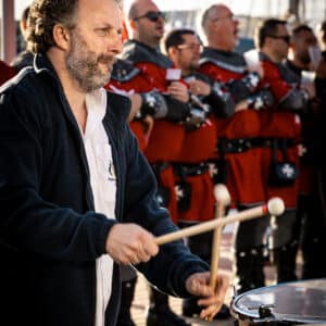 Hombre tocando tambor en desfile medieval.
