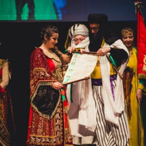 Personas con vestimenta tradicional entregando pergamino en ceremonia