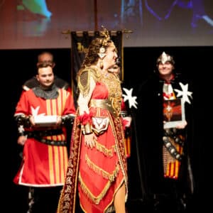 Personas vestidas con trajes medievales en un escenario.