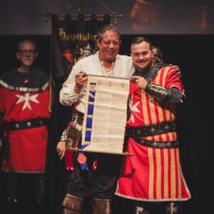 Ceremonia medieval con personajes, pergamino y escudo.