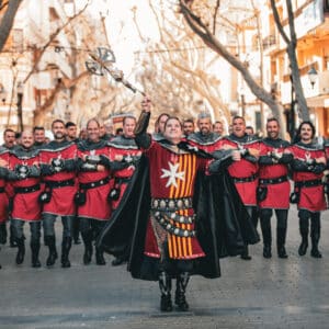 Desfile medieval en traje rojo y negro.