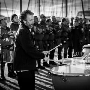 Hombre toca timbales en desfile medieval al aire libre.