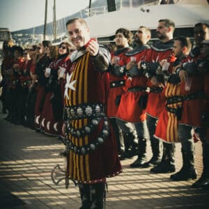 Grupo de personas en atuendos medievales en un puerto.