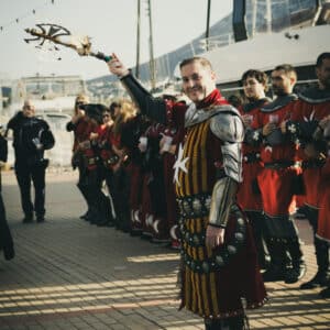 Persona en disfraz medieval liderando grupo en puerto