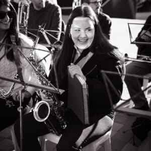 Músico sonriente con saxofón en ensayo al aire libre.