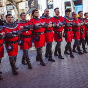 Hombres con trajes medievales desfilando en la calle.