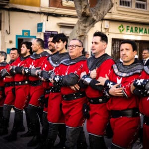Grupo de hombres con trajes medievales rojos en desfile.