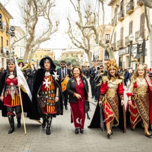 Desfile medieval con trajes tradicionales en una calle urbana.