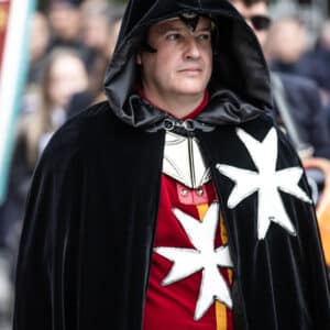 Hombre con capa negra y cruz blanca