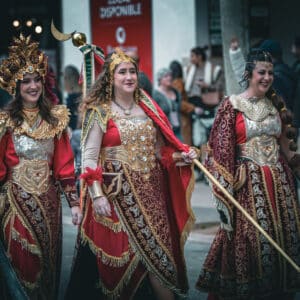 Desfile de mujeres con trajes medievales coloridos.