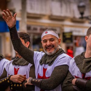 Personas en desfile medieval saludando alegres