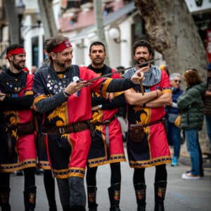 Hombres disfrazados desfilan en festival medieval.