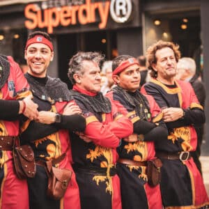 Grupo de personas en trajes medievales rojos y negros.