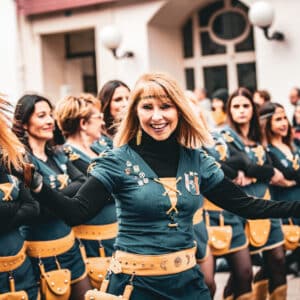 Mujer sonriendo en desfile con vestimenta tradicional.