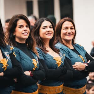 Mujeres sonriendo en trajes tradicionales en desfile.
