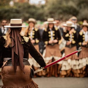 Mujer liderando grupo folclórico en desfile tradicional