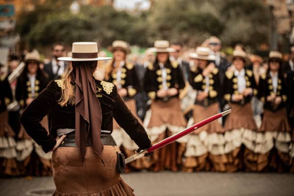 Mujer liderando grupo folclórico en desfile tradicional