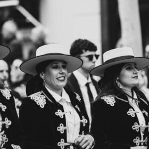 Mujeres con trajes y sombreros en desfile folclórico.