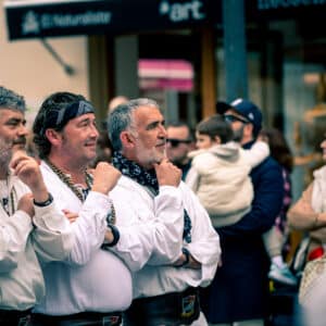 Hombres en ropa tradicional observando desfile.