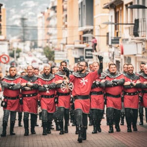 Desfile de hombres en trajes medievales por la calle.