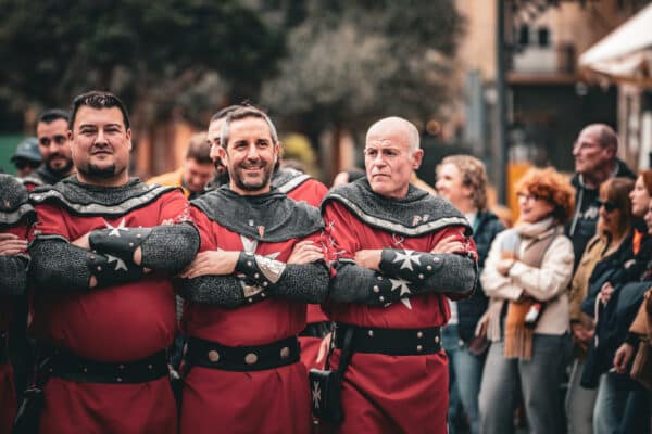 Hombres con trajes medievales en desfile histórico.