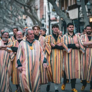Personas en desfile con túnicas a rayas.