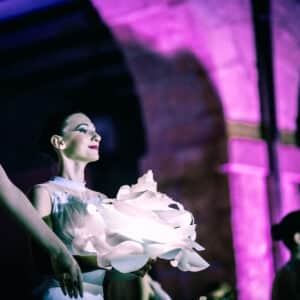 Bailarina en escenario con luz tenue y flores.