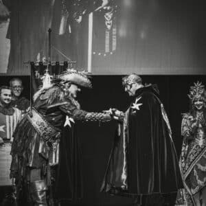 Evento medieval con trajes históricos en un escenario.