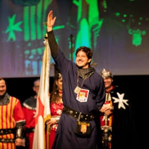 Hombre medieval sonriendo, levantando la mano en escenario