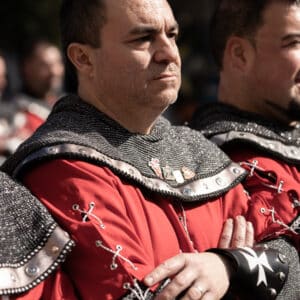 Hombre con traje medieval rojo y negro.