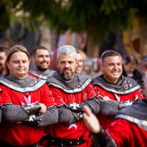 Hombres disfrazados de caballeros medievales en desfile.