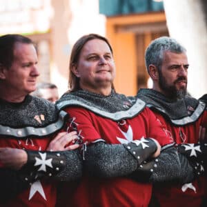 Hombres medievales con armaduras rojas y estrellas blancas.