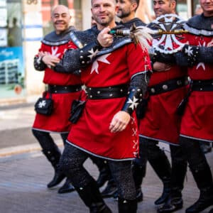 Hombres en trajes medievales desfilando en la calle.