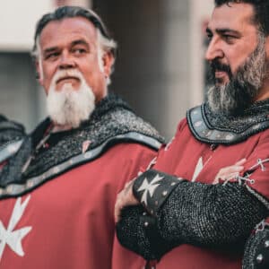 Hombres disfrazados de caballeros medievales con cruces blancas.