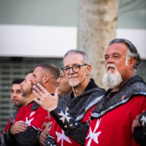 Hombres en trajes medievales rojos con cruces blancas.