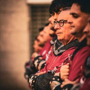Personas en fila con trajes medievales rojos.