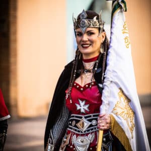Mujer en vestimenta festiva con bandera ceremonial.