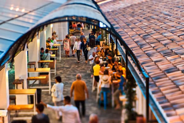 Gente caminando en mercado al aire libre.